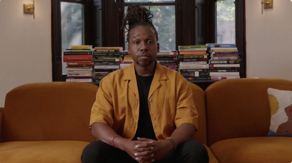 Maurice Mitchell, a Black man, sits on a couch facing the camera.
